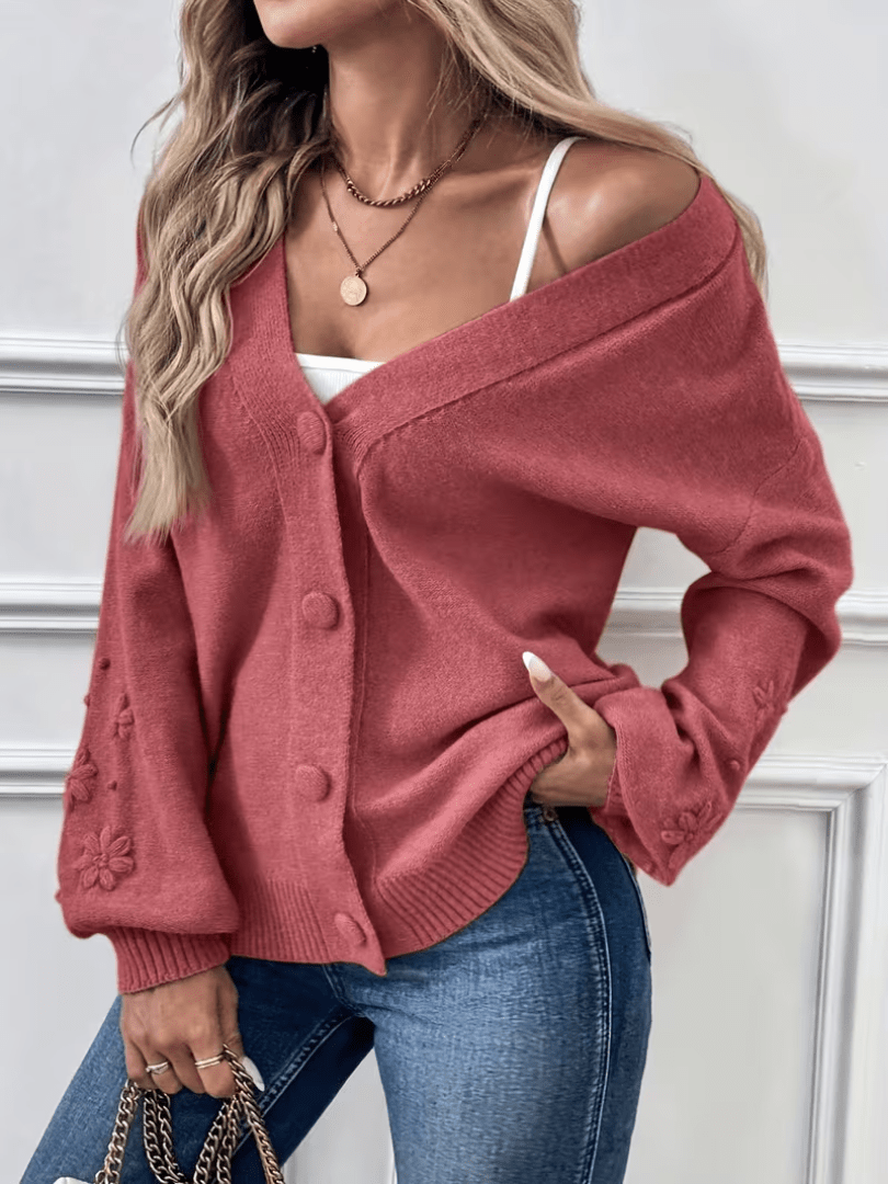 Gilet rose pâle à col V, boutons devant, fleurs en relief sur les manches.