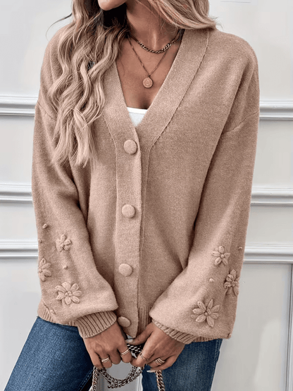 Gilet beige à col V, boutons devant, poignets et manches décorés de fleurs.