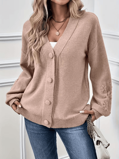 Gilet beige à col V, boutonné, manches et poignets avec décor floral en relief.