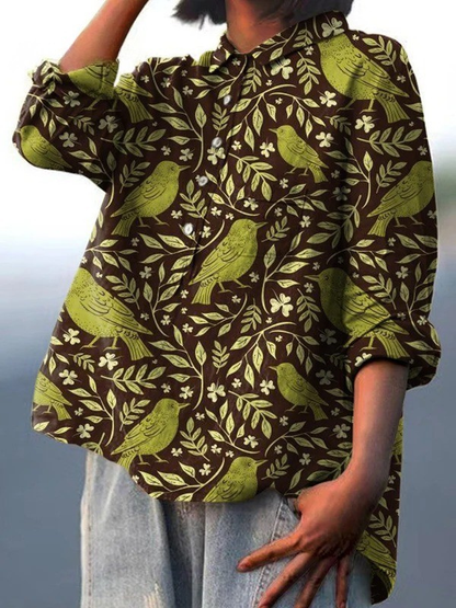 Chemise ample à manches longues, motif oiseaux et feuilles vert olive sur fond sombre.