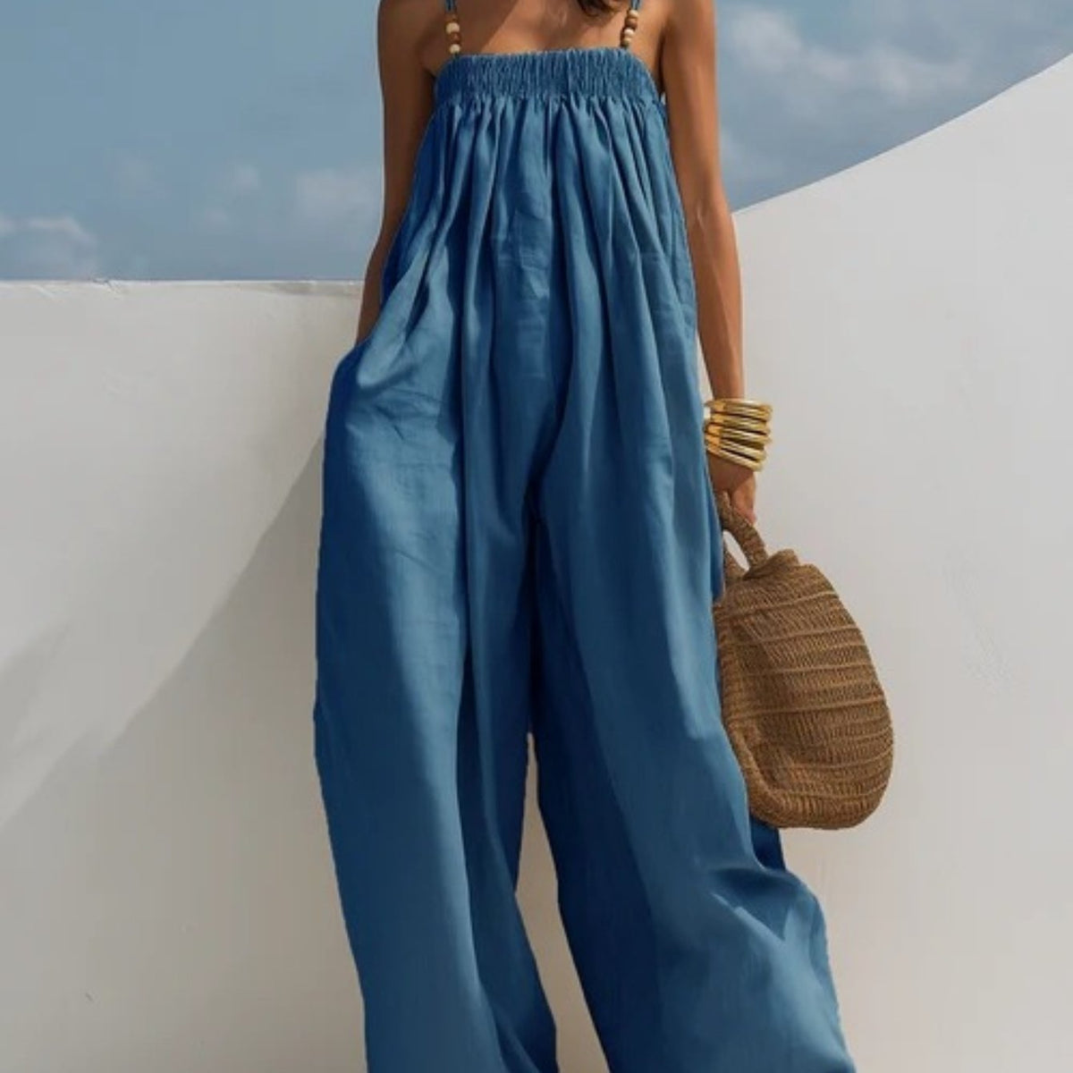 Combinaison en denim bleu ample, taille froncée et jambes larges fluides.