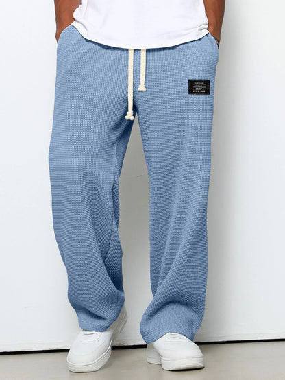 Pantalon pour hommes à coupe confortable bleu clair, taille à cordon, devant fendu, étiquette.