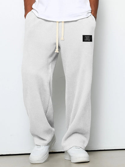 Pantalon pour hommes à coupe confortable blanc cassé, taille à cordon, devant fendu, étiquette.