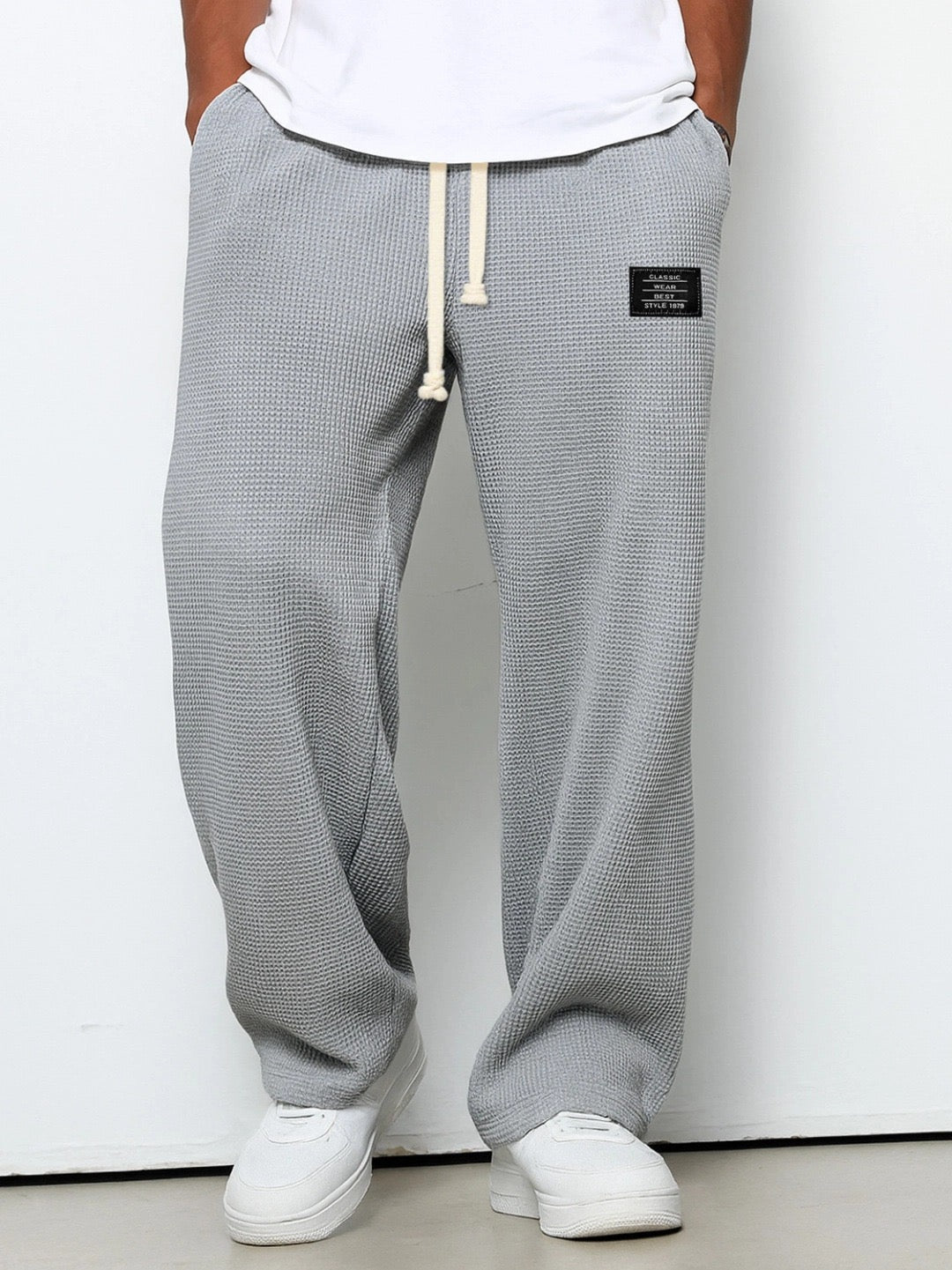 Pantalon pour hommes à coupe confortable gris, taille à cordon, devant fendu, étiquette.