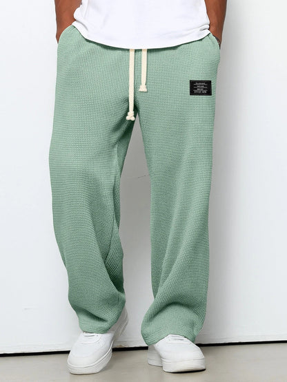 Pantalon pour hommes à coupe confortable vert, taille à cordon, devant fendu, étiquette.