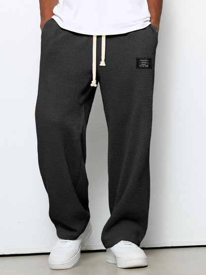 Pantalon pour hommes à coupe confortable noir, taille à cordon, devant fendu, étiquette.