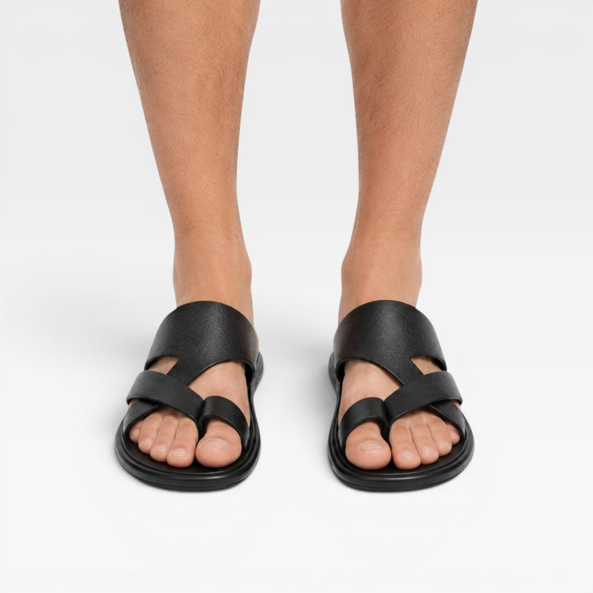 Sandales en cuir noires à enfiler avec boucle d’orteil, portées pieds nus