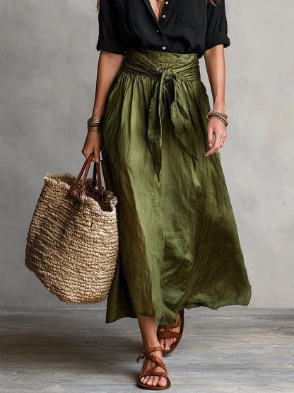 Haut noir boutonné, jupe mi-longue vert olive à taille froncée et lien noué