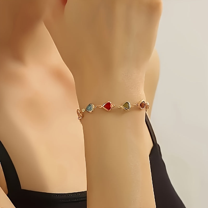 Bracelet à cœurs émaillés colorés sur poignet, fermoir visible.