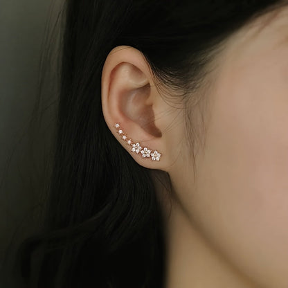 Boucles d’oreilles florales en or rose, motif en rangée de petites fleurs, vue portée