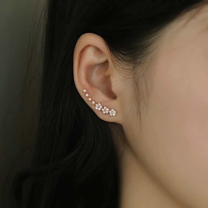 Boucles d’oreilles fleurs en strass rosé, portées, motif floral le long de l’oreille.