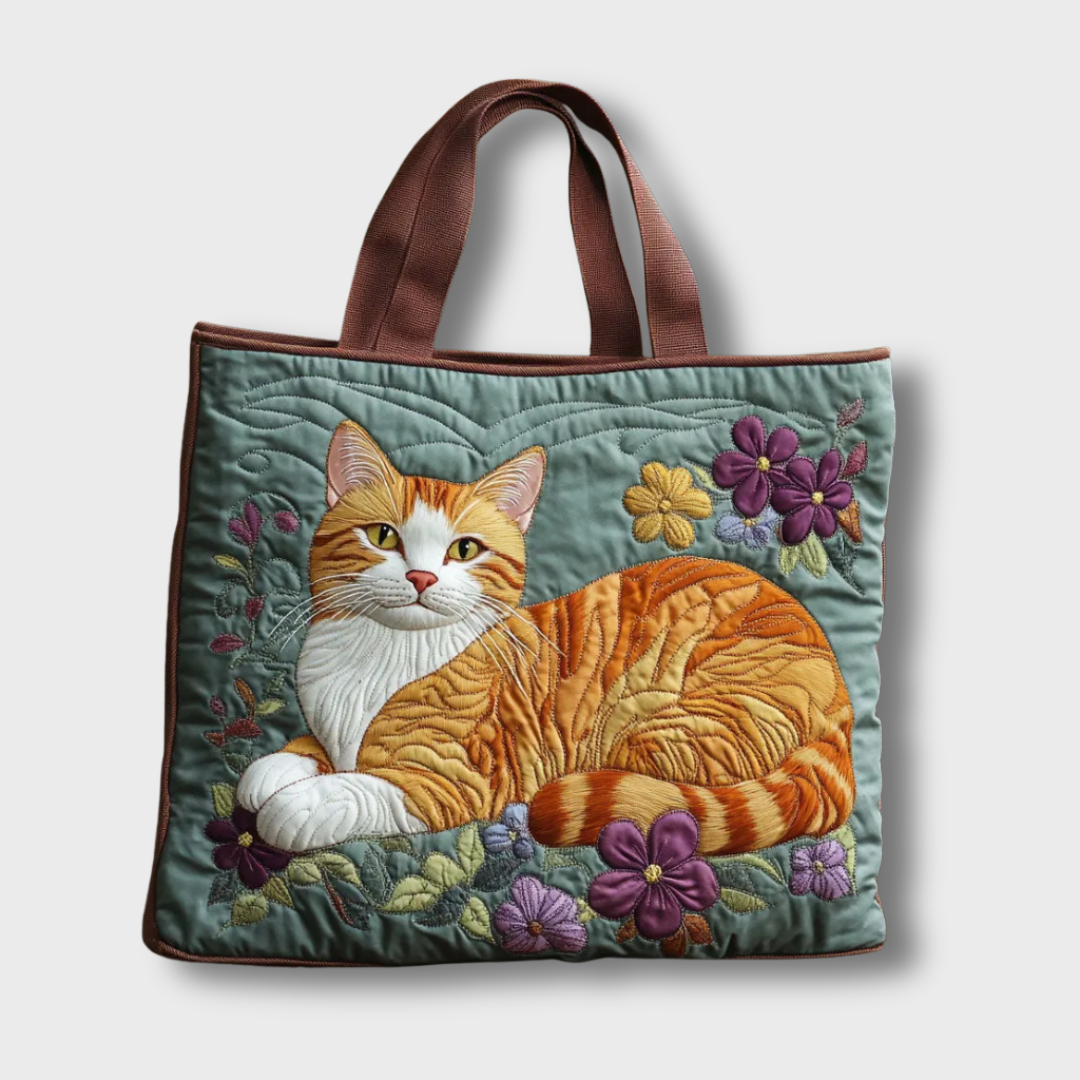 Sac à main fait main matelassé vert, anses marron, applique chat roux et fleurs violettes.