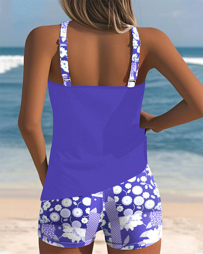 Ensemble tankini violet à bretelles, avec short imprimé fleurs bleues et blanches.