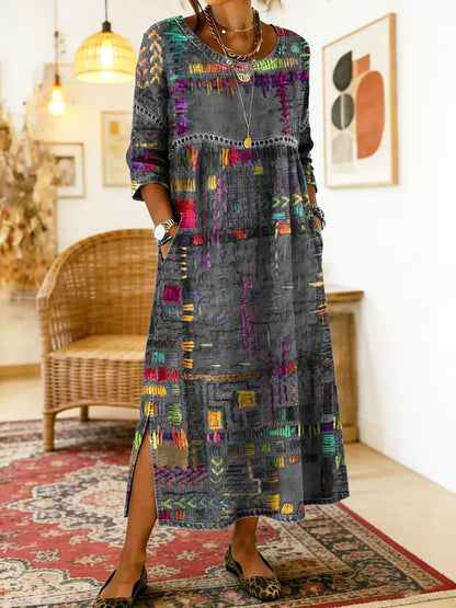 Robe longue patchwork en jean multicolore sur fond gris, motifs ethniques visibles.