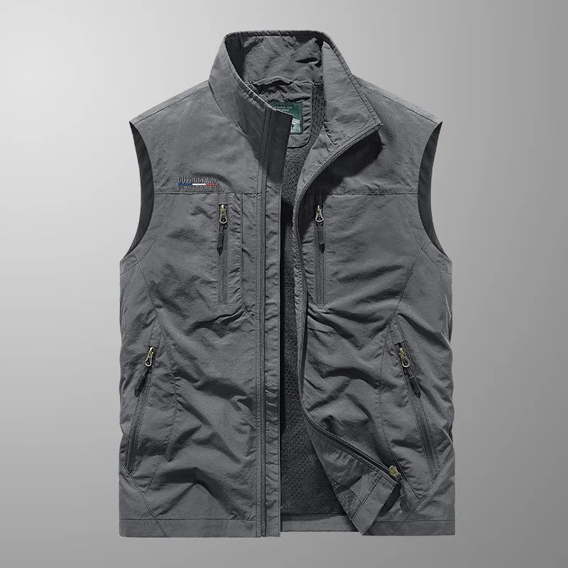Gilet sans manches gris, fermeture zippée et poches zippées sur la poitrine et le bas.