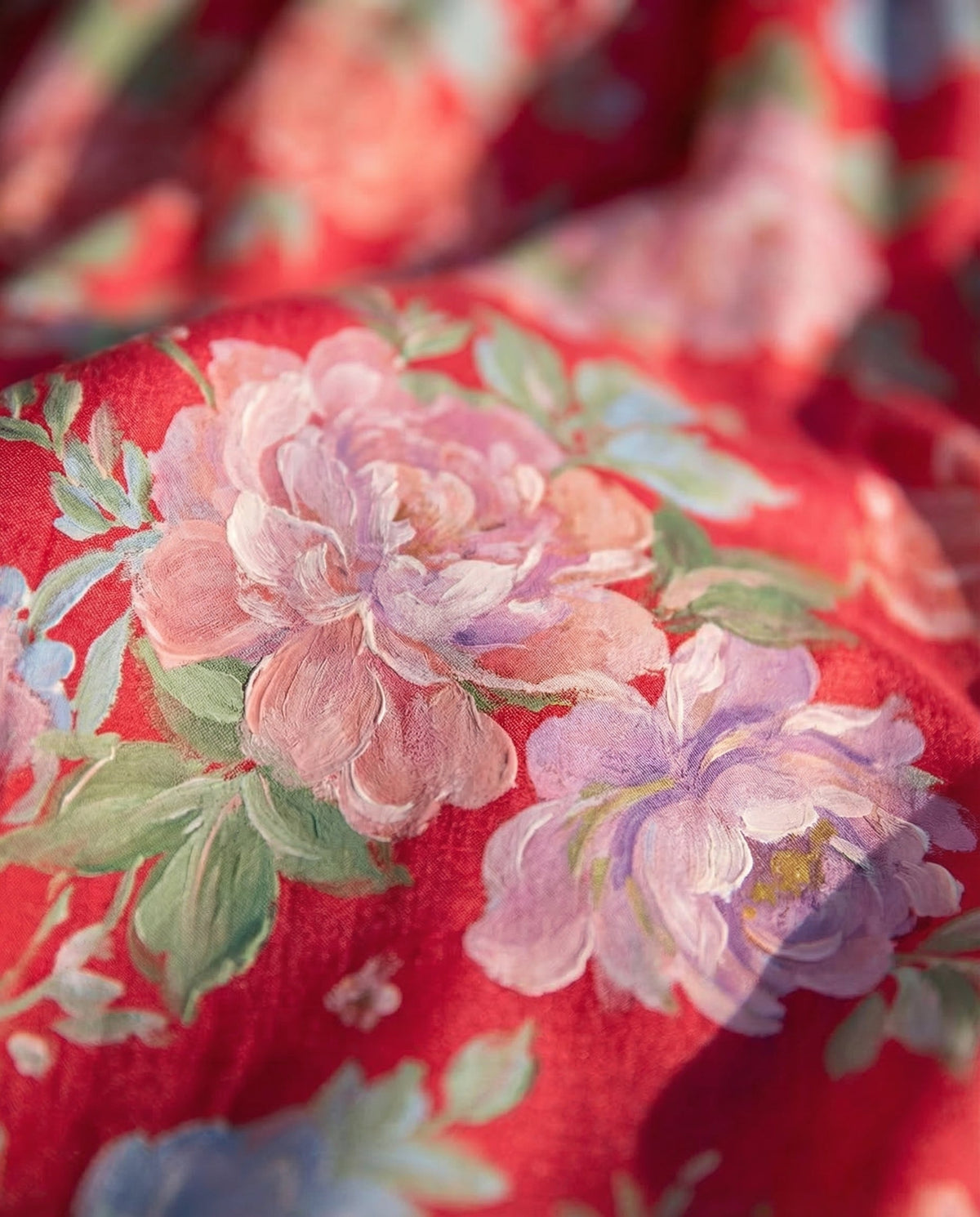 Tissu de robe rouge à fleurs roses et violettes, gros plan sur motifs floraux