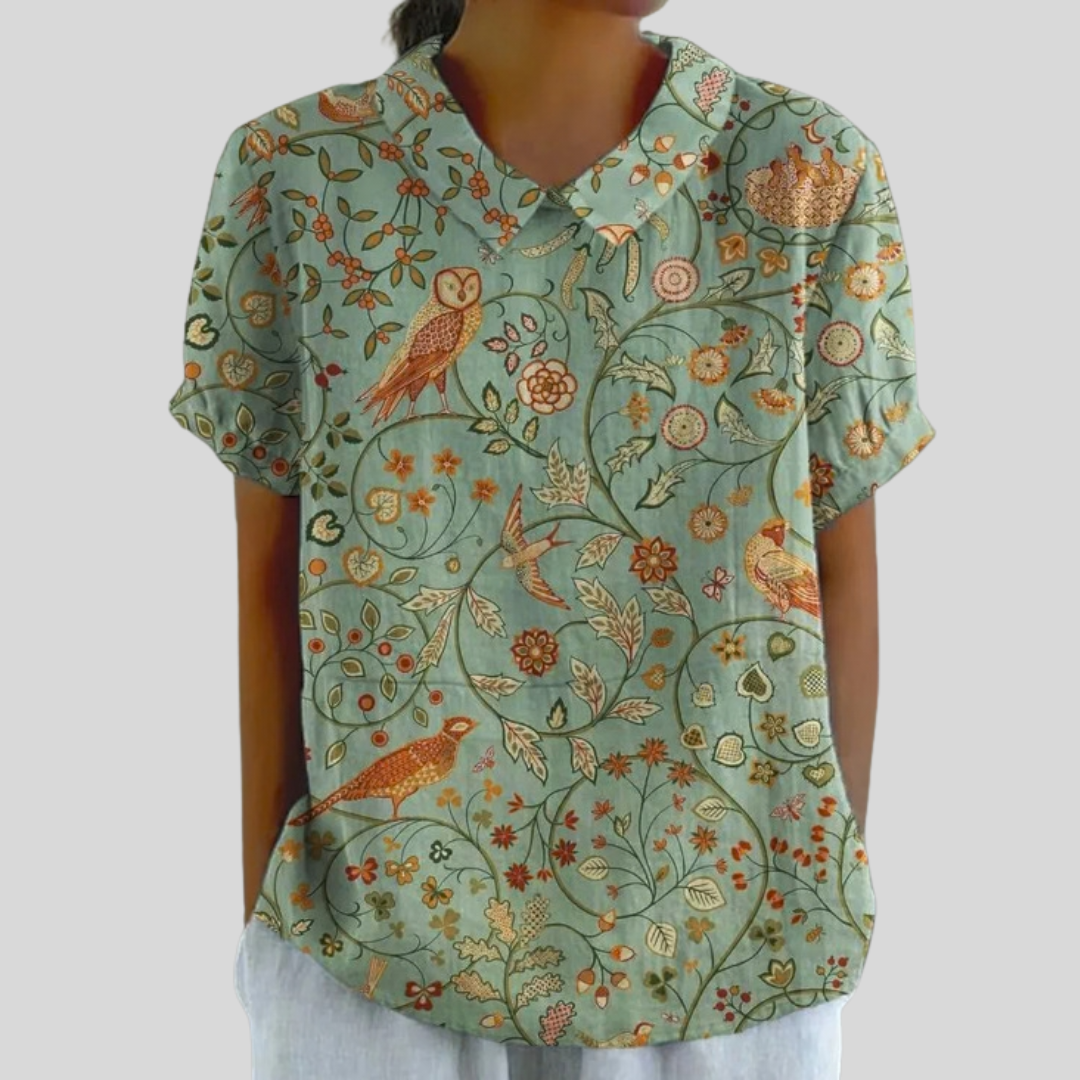 Blouse Apolline à col tunisien manches courtes, fond bleu clair imprimé oiseaux et fleurs