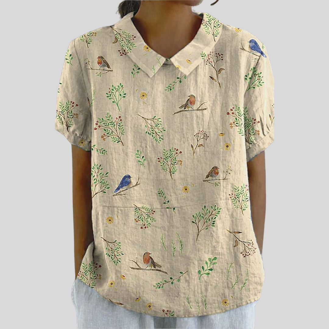 Blouse en lin beige à col chemise, imprimé oiseaux et fleurs, manches courtes bouffantes.