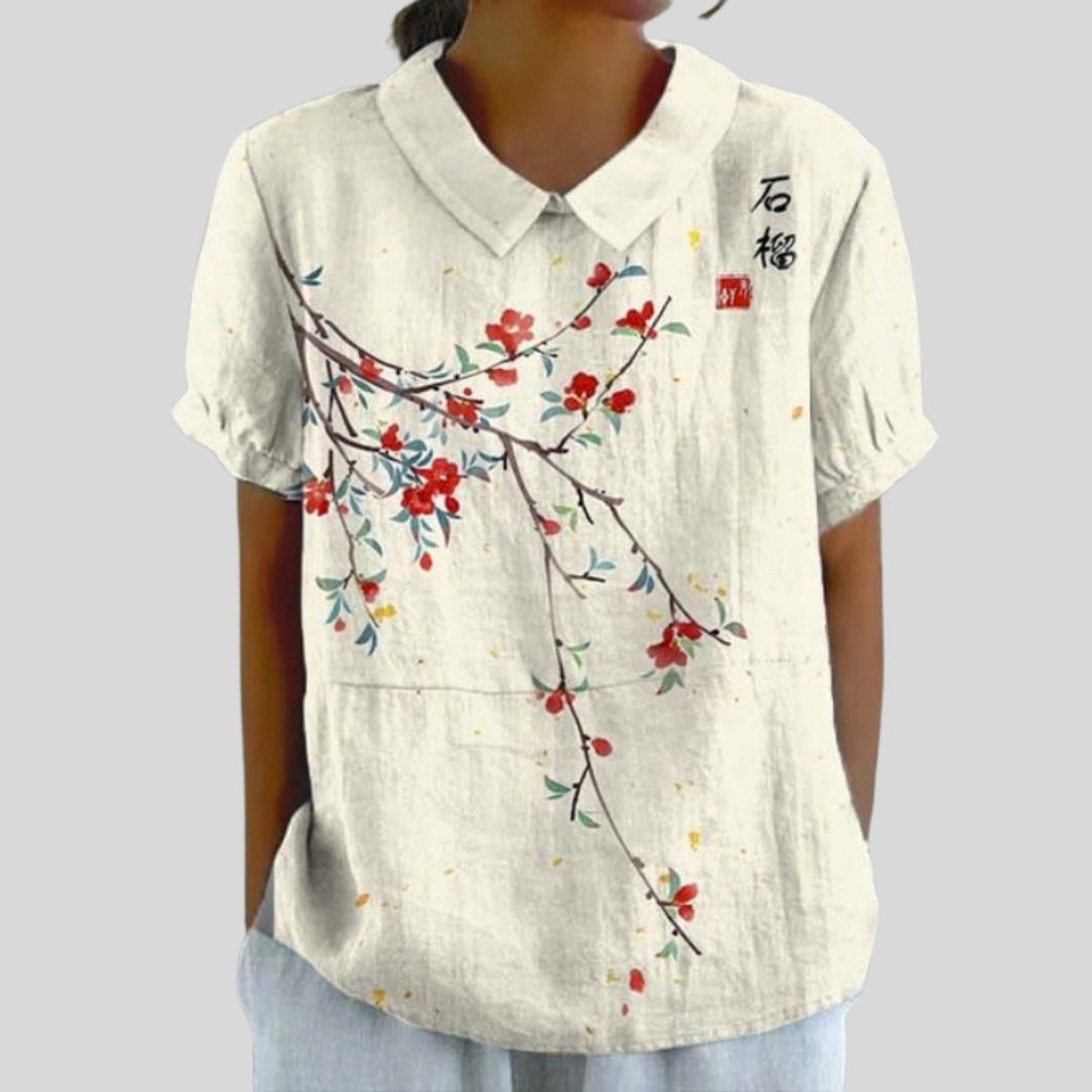 Blouse blanche en lin avec motif floral rouge et bleu, col simple.