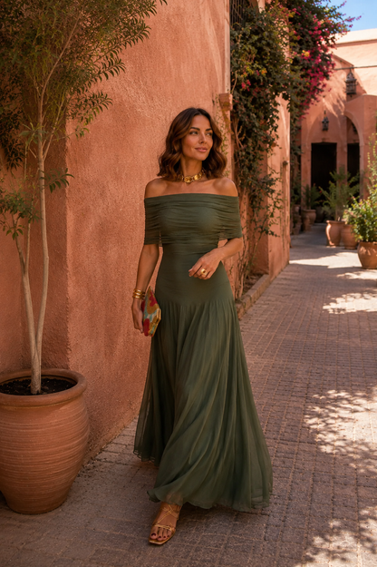 Robe longue vert olive épaules dénudées, buste froncé et jupe évasée, tenue avec pochette colorée.