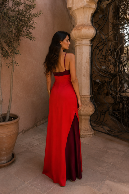 Robe longue rouge au dos, bretelles fines et fente latérale, buste bordeaux.