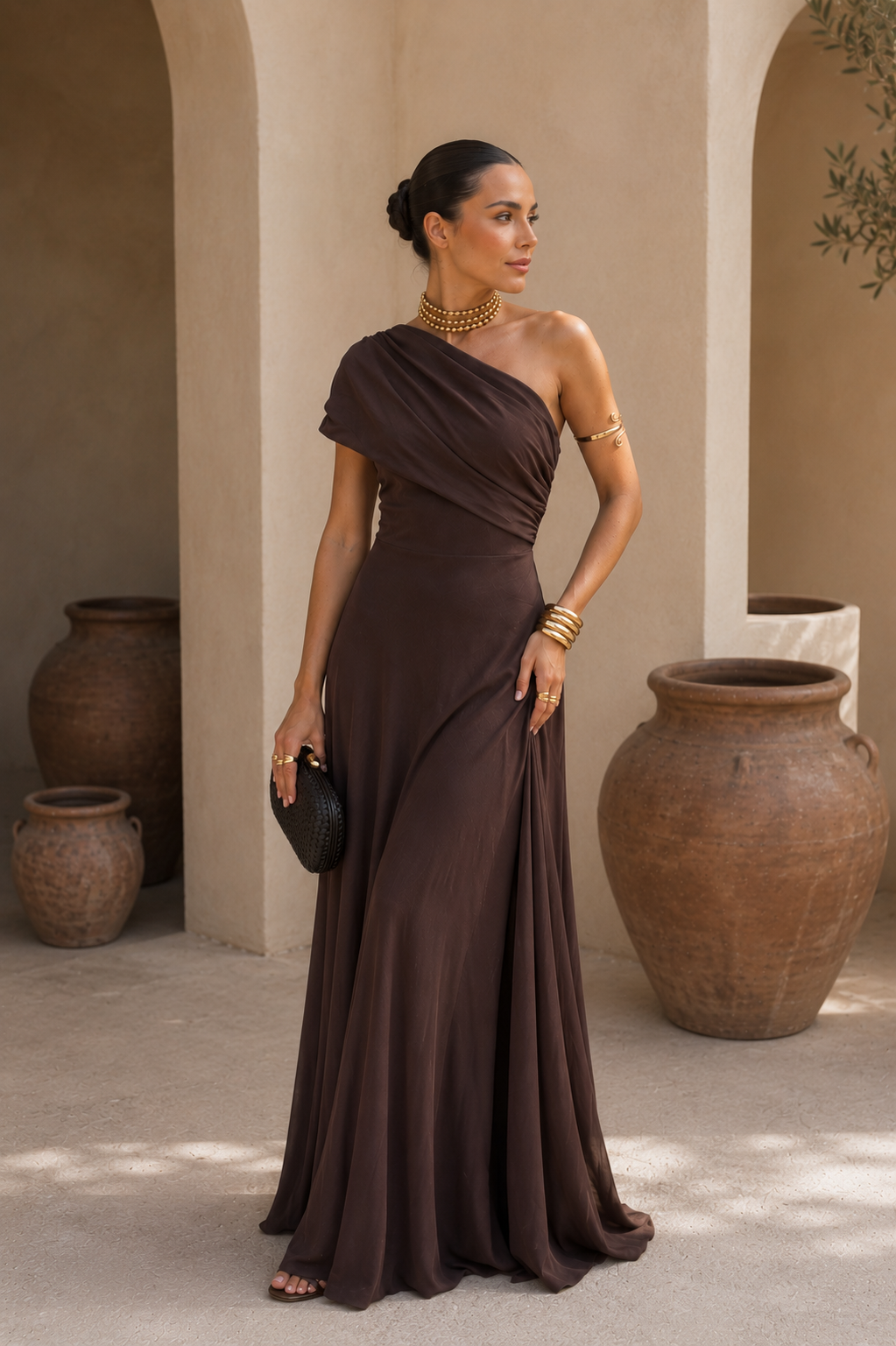 Robe longue marron foncé drapée à une épaule, silhouette ajustée et jupe évasée.