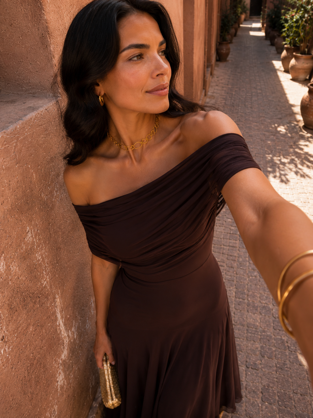 Robe marron foncé à drapé asymétrique, gros plan sur buste et col fin.