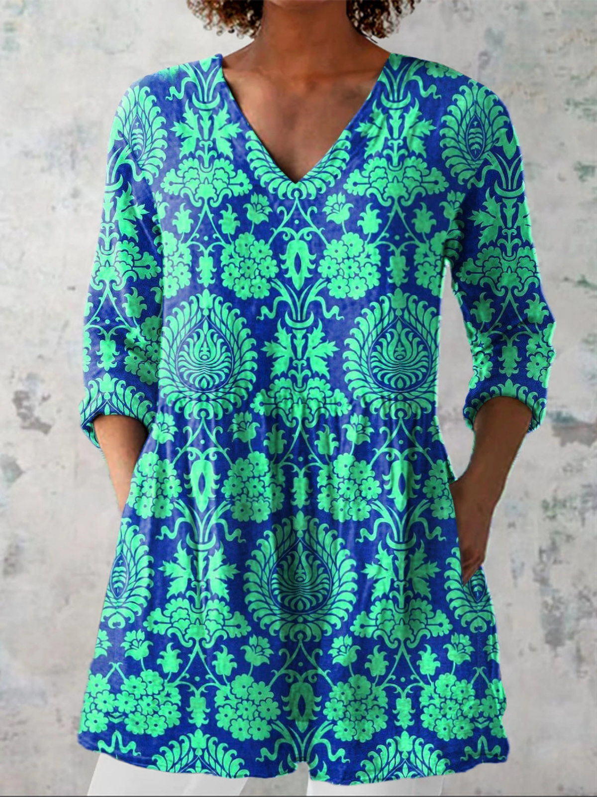 Blouse longue sarcelle à décolleté en V, manches trois-quarts, motif fleuri et arabesques.