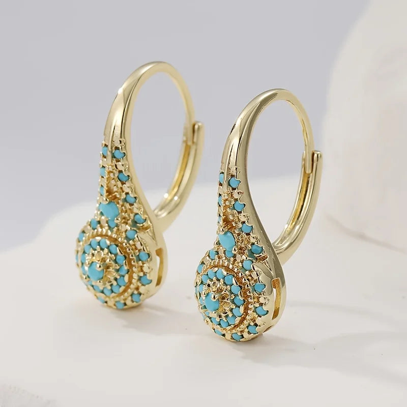 Boucles d’oreilles créoles dorées turquoise, vue de profil avec motif floral