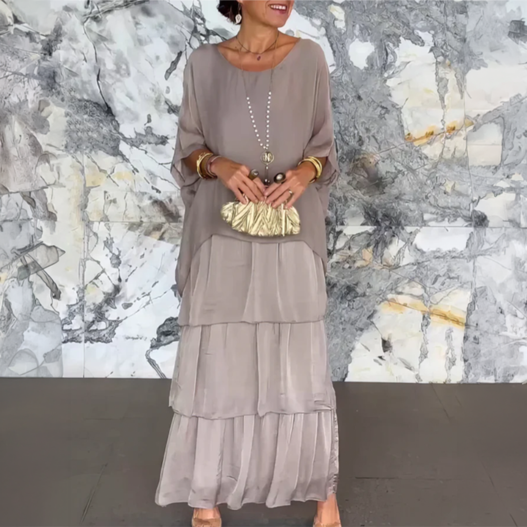 Robe longue fluide grise, manches chauve-souris, volants superposés, col ras du cou