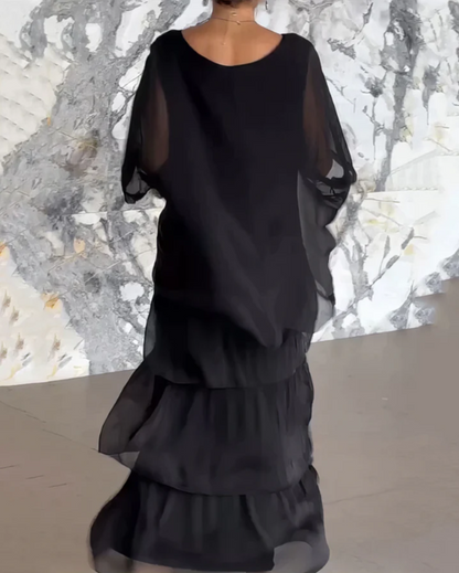 Robe longue fluide noire, manches en voile transparent, volants superposés au bas