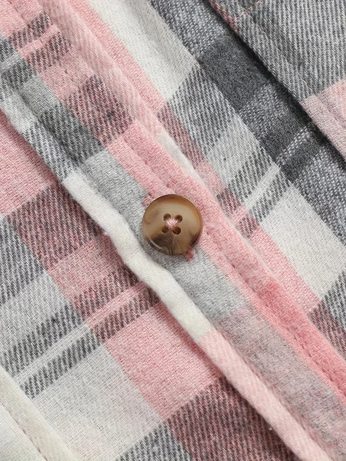 Gros plan chemise d’été à carreaux rose et gris, bouton en résine, couture visible