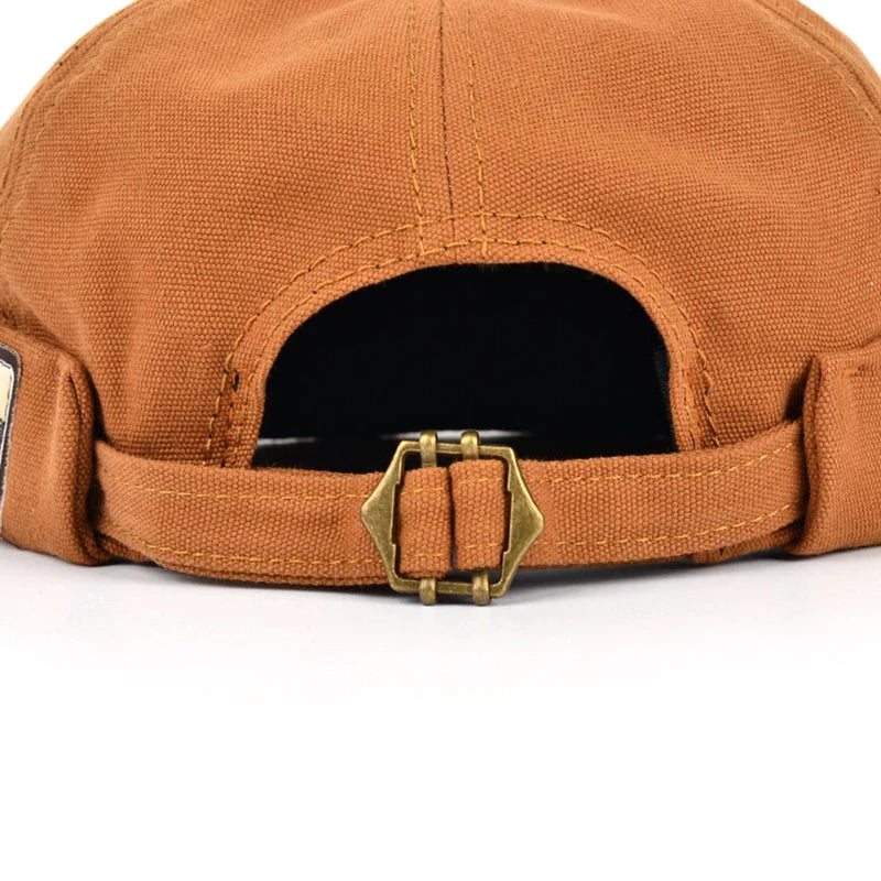 Casquette orange pour animal : ouverture, intérieur noir, sangle réglable et boucle.