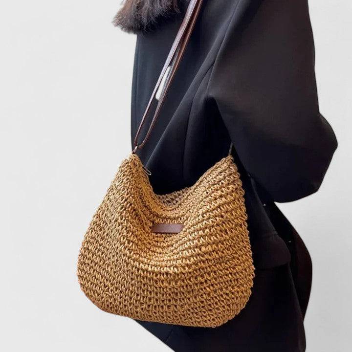 Sac en paille dorée avec bandoulière marron, porté sur l’épaule, motif rectangulaire.
