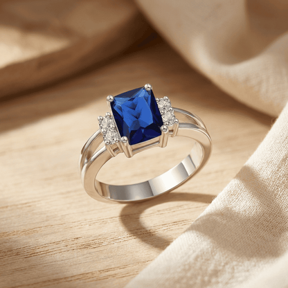Bague en or blanc avec saphir bleu octogonal et entourage de pierres, vue en biais