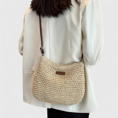 Sac élégant en paille beige porté en bandoulière, devant avec petit patch rectangulaire.